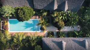 An aerial view of a resort with a swimming pool surrounded by lush greenery and palm trees. - Kuwa Zanzibar (Kiwengwa)