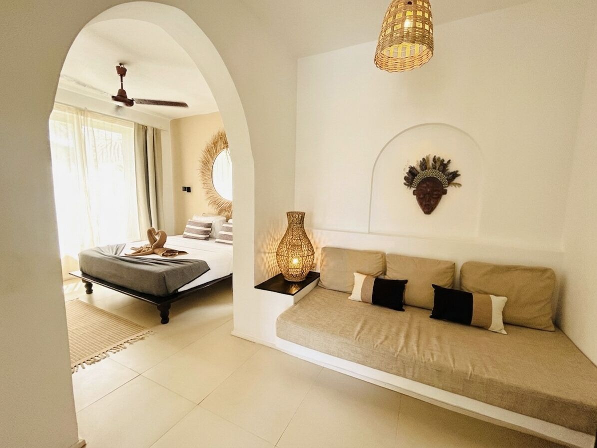 A modern living room with a sofa, a small table with a lamp, and a decorative wall piece.