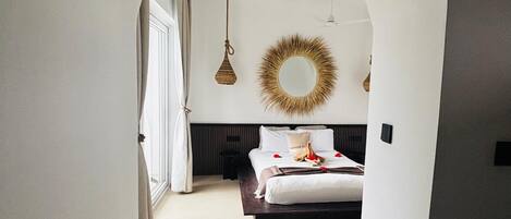 A bedroom with a bed, a mirror, and a hanging light fixture.