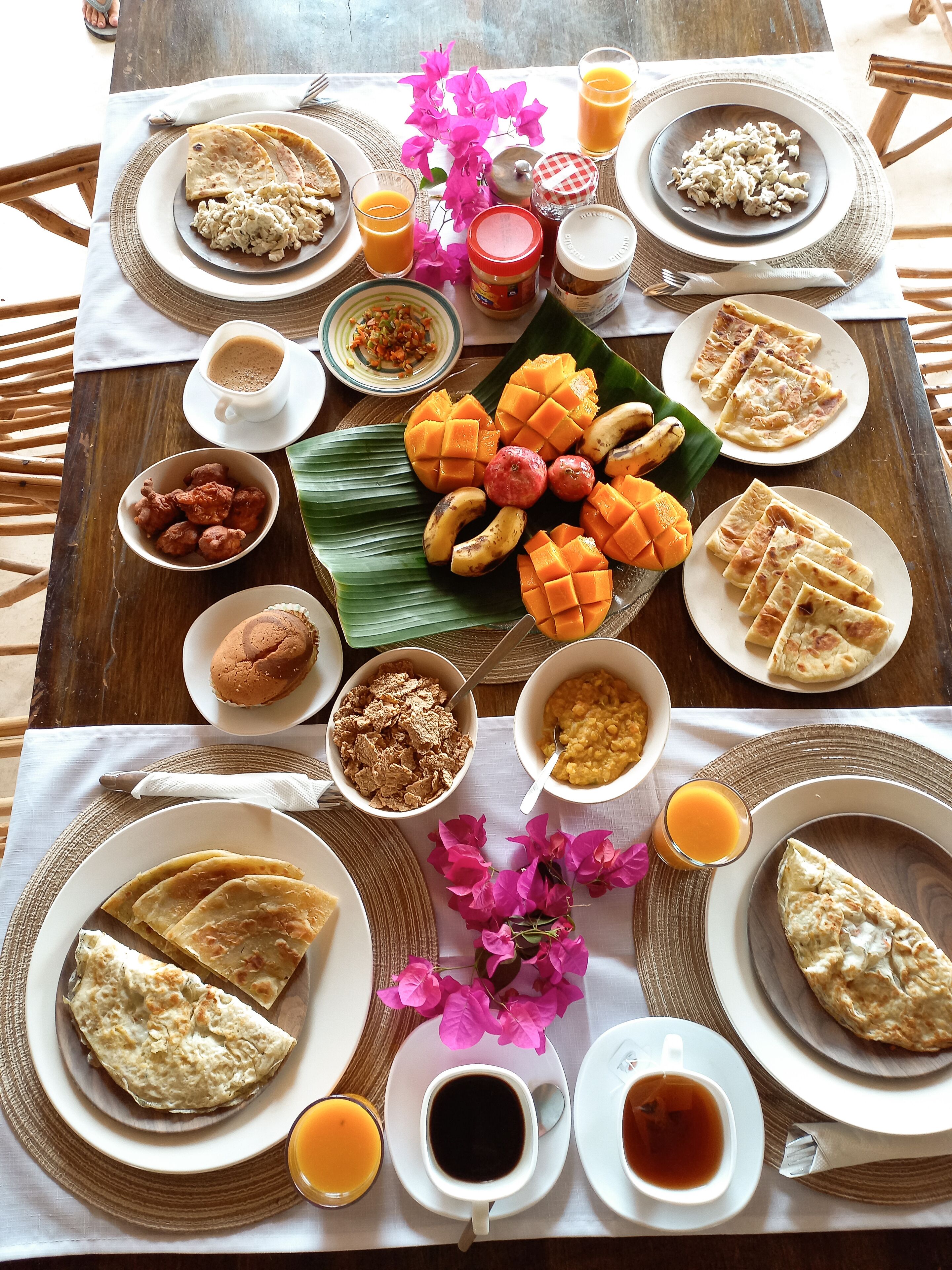 A table set with various breakfast items including bread, fruits, and beverages.