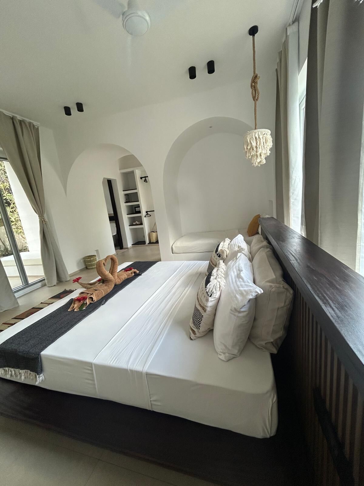 Un dormitorio moderno con una cama grande, una araña y vistas al exterior.