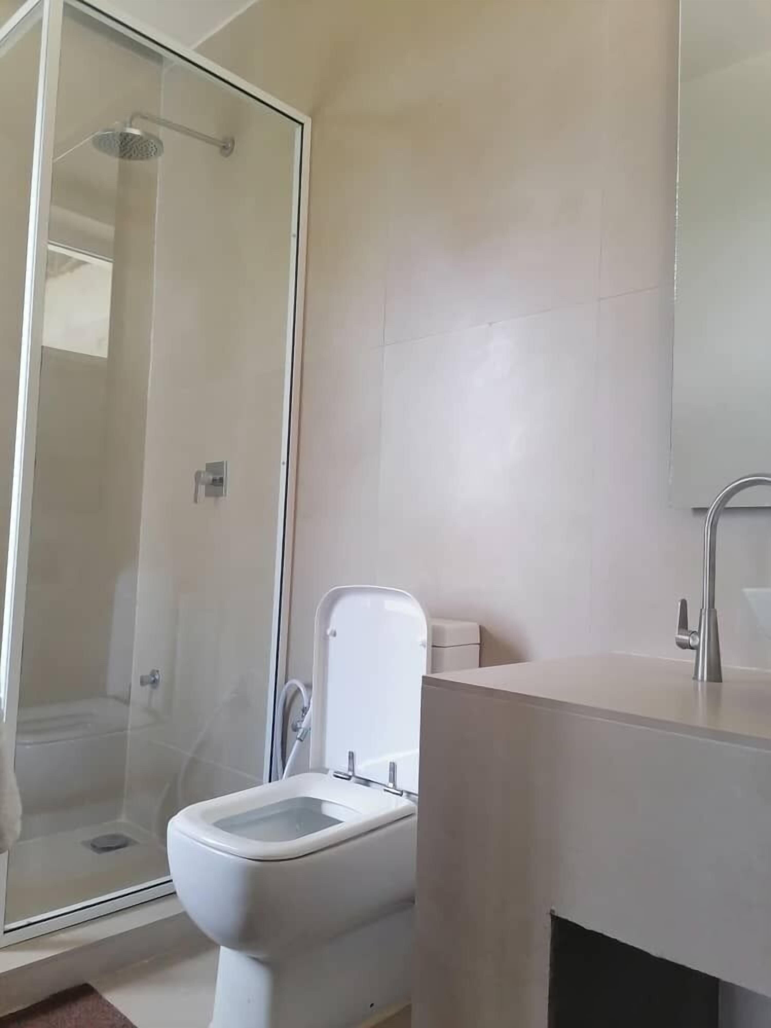 A bathroom with a glass-enclosed shower, a toilet, and a sink with a mirror.