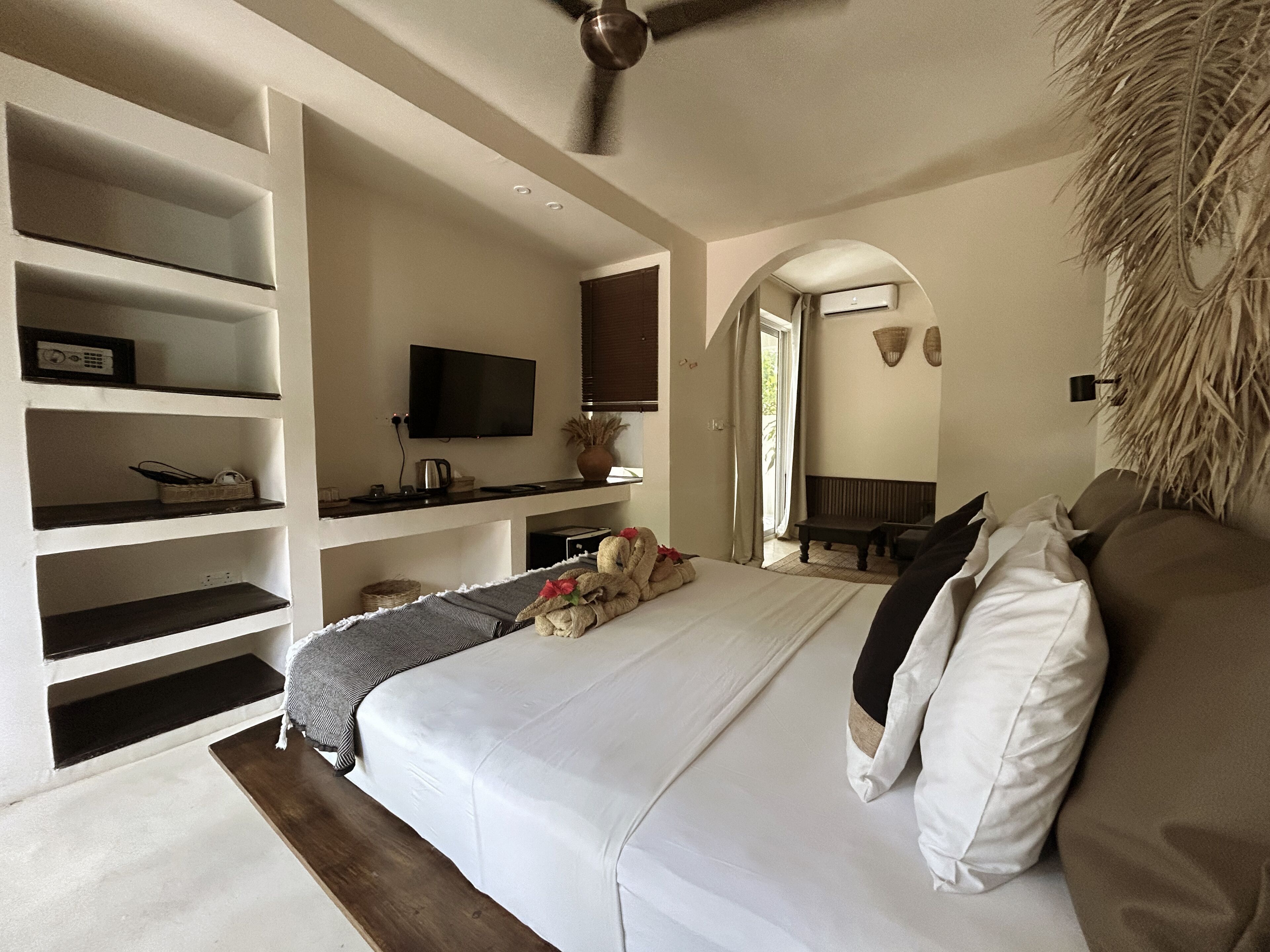 Ein Schlafzimmer mit einem großen Bett, einem Fernseher, einem Deckenventilator und eingebauten Regalen.