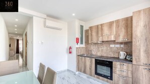 Eine moderne Küche mit Holzschränken, einem Einbauofen und einer Marmorarbeitsplatte.