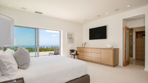A modern bedroom with a large bed, a desk, and a view of the ocean. - Jewel by AvantStay | Panoramic Ocean Views in La Jolla! (San Diego)