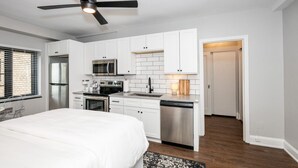 Una cocina moderna con gabinetes blancos, electrodomésticos de acero inoxidable y un ventilador de techo.
