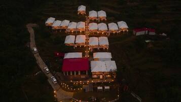 An aerial view of a resort with multiple dome-shaped buildings, a central building with a red roof, and a well-lit pathway.