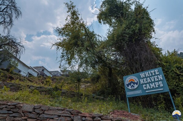 A sign for White Heaven Camps with a logo, a website URL, and a phone number. - White Heaven Camps (Ukhimath)