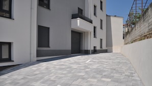 Un edificio moderno con un diseño limpio y geométrico, que presenta un patio empedrado y una fachada blanca con detalles oscuros.