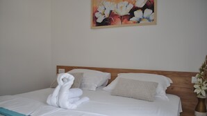 Una cama bien hecha con sábanas blancas, una manta azul y una decoración de toallas con forma de cisne.