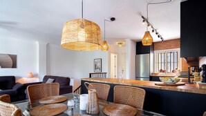 Una cocina moderna con una isla central, sillas de mimbre y una mesa de comedor de vidrio.