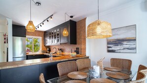 Una cocina moderna con armarios oscuros, una isla grande y sillas de mimbre.