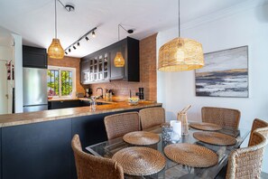 A modern kitchen with dark cabinets, a large island, and wicker chairs.