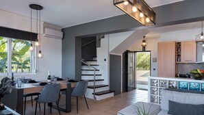 A modern kitchen with a dining area, a staircase, and a living room with a sofa and a coffee table. - Steps from Maleme beach, walking distance to shops, private pool! (Chania)