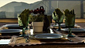 Une table mise pour un repas, avec de la verrerie verte, des assiettes et une plante en pot.
