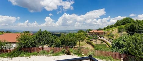 Un balcón con vistas a una zona residencial, que incluye casas y vegetación.