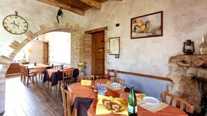 Un comedor rústico con mesas y sillas de madera, una pared de piedra y un reloj en la pared.