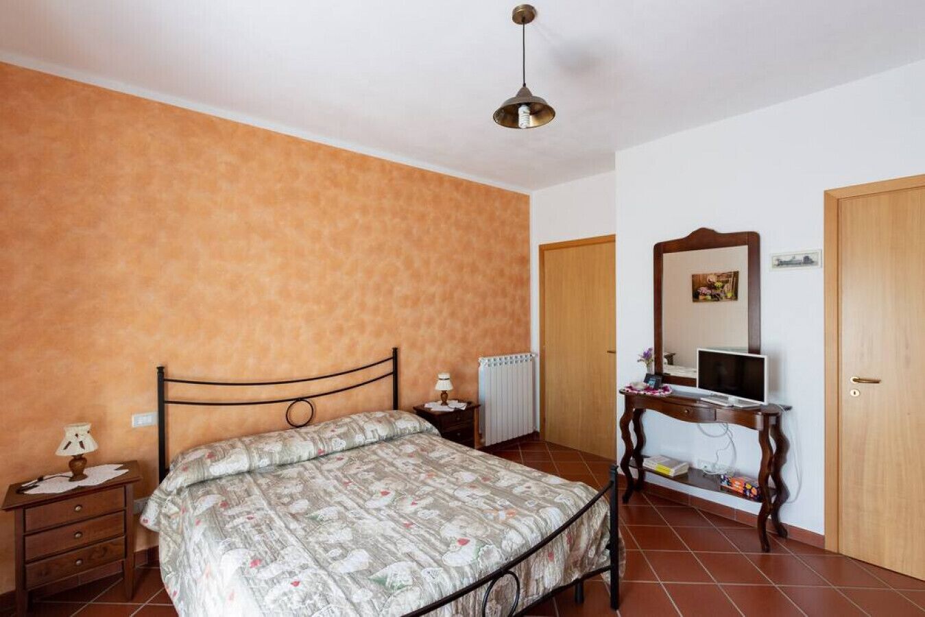 A bedroom with a bed, a dresser, a mirror, and a radiator.