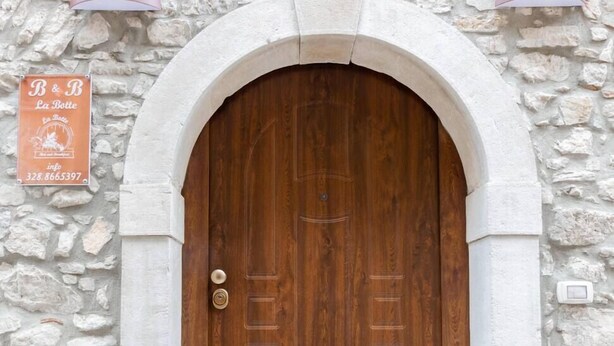 A wooden door with a stone wall and a sign above it.