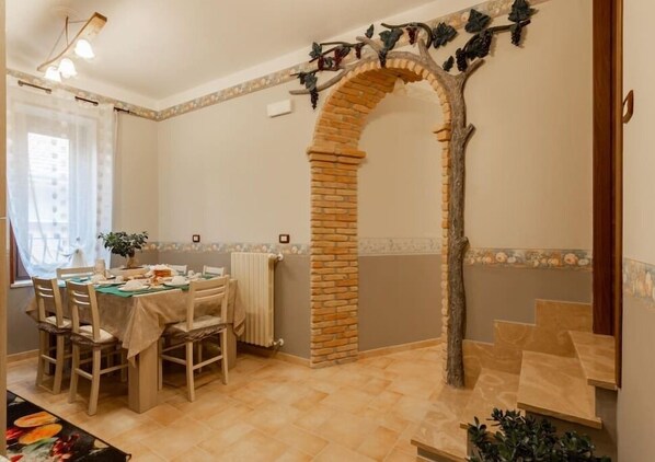 A dining area with a brick archway, a table set for four, and a radiator.