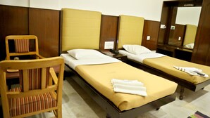 Una habitación de hotel con dos camas individuales, una silla de madera y un espejo.