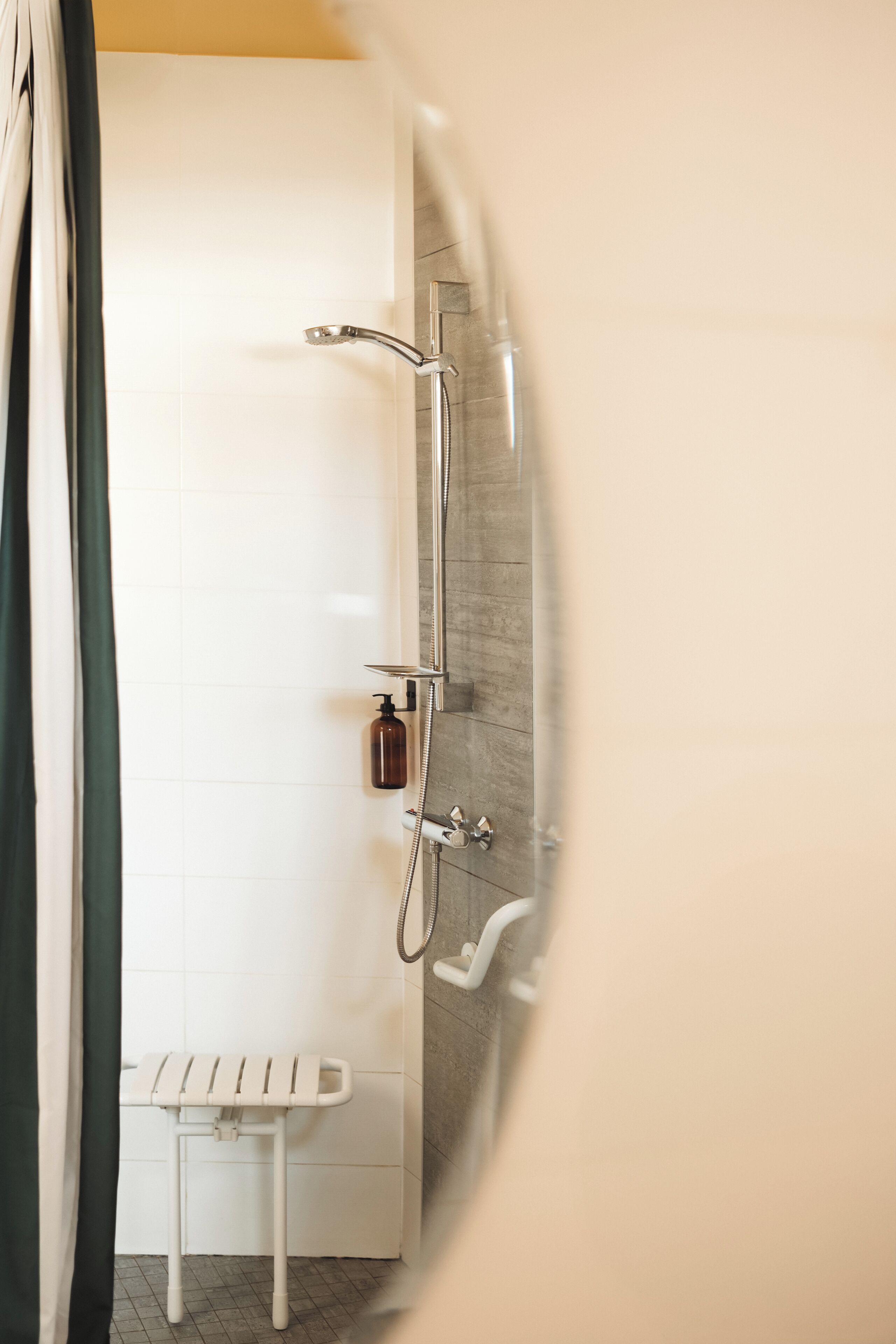 Un bagno con doccia, un portasciugamani bianco e una bottiglia di sapone.