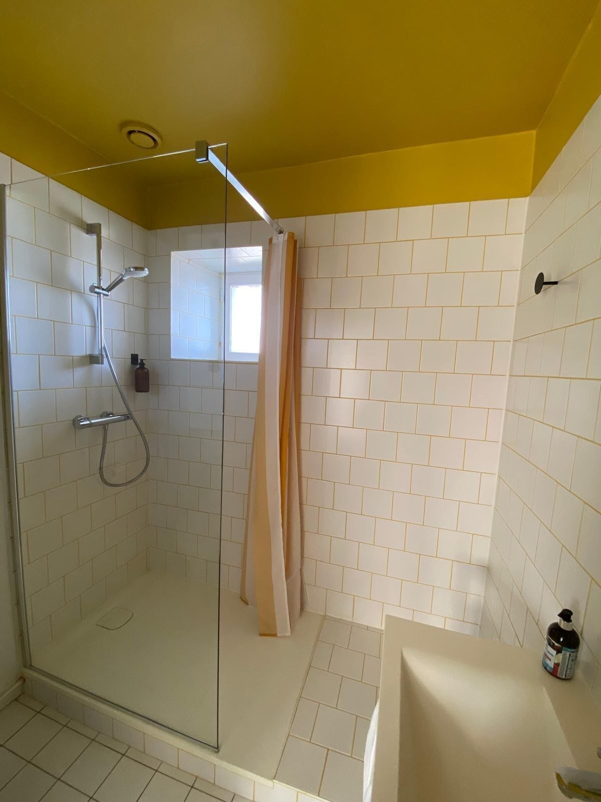 A shower with a glass door, a handheld showerhead, and a shower curtain.