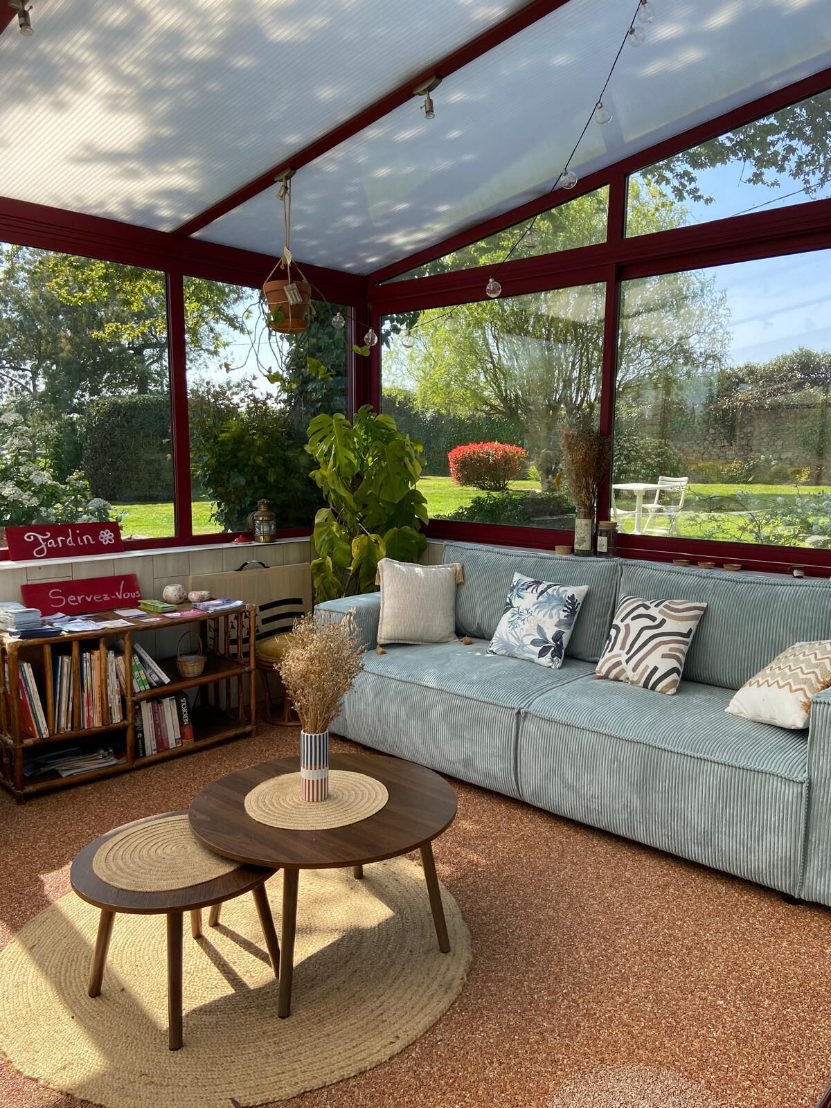 Une pièce confortable avec une grande fenêtre, un canapé, une table basse et une bibliothèque.
