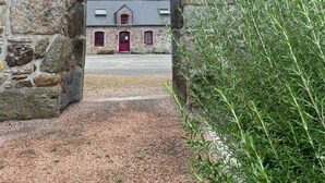 Un arco de piedra que conduce a un edificio con una puerta roja y un ventanal pequeño.