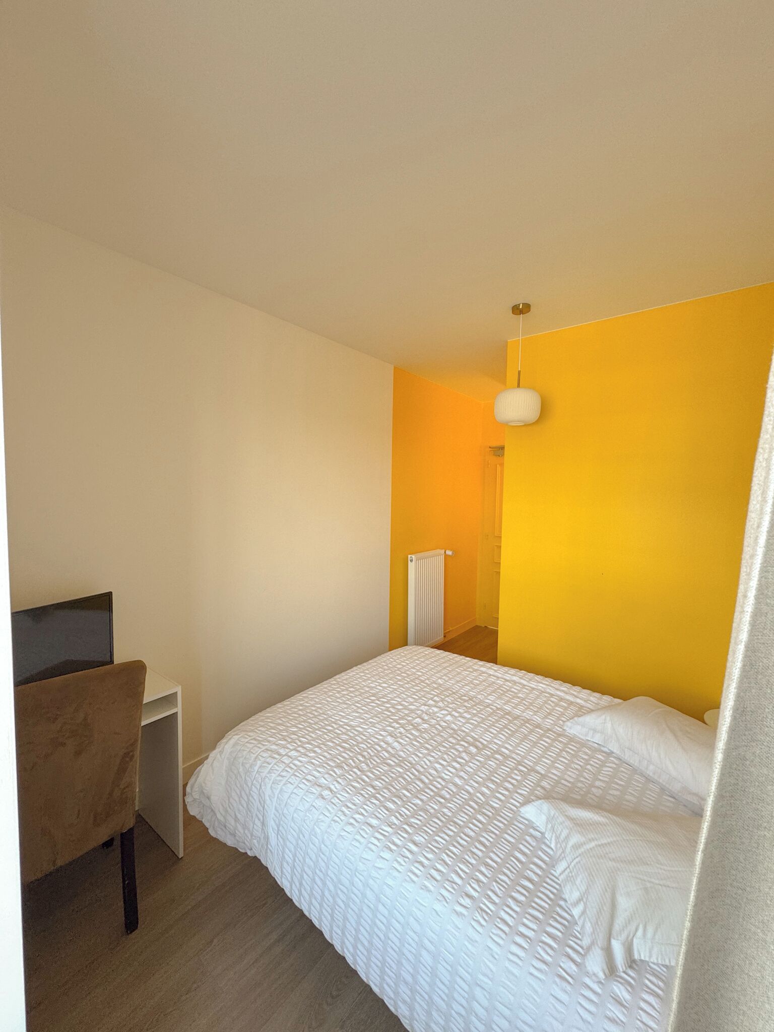 A bedroom with a bed, a desk, and a chair.