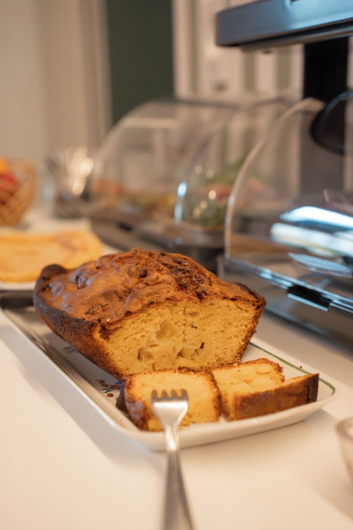 Une part de gâteau sur une assiette, avec une fourchette à côté, un récipient en verre et un four à micro-ondes en arrière-plan.