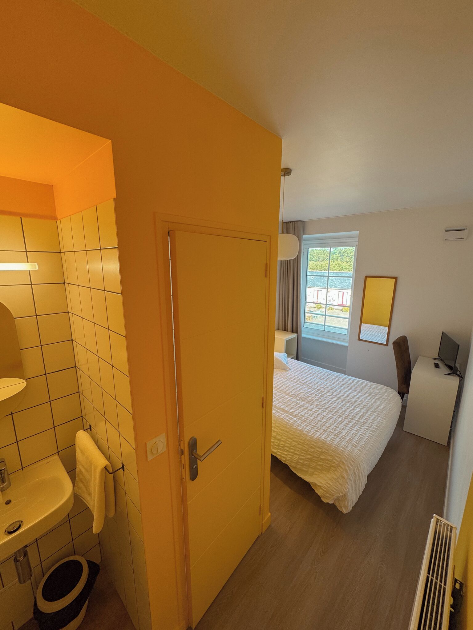 Een hotelkamer met een badkamer, een bed, een bureau en een raam.
