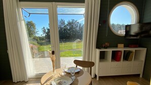 Una habitación con una mesa de comedor para dos personas, un sofá, un televisor y vistas al exterior.