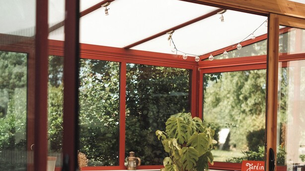 Una habitación iluminada por el sol con un ventanal grande, un sofá, una mesita de centro y una mesa de comedor.