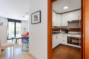 A modern kitchen with white cabinets, a built-in oven, and a dining area with a table and chairs. - Apartment 'El Ático De La Montaña' with Balcony, Wi-Fi and Air Conditioning (Málaga)