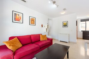 A modern living room with a red sofa, black coffee table, and framed pictures on the wall. - Apartment 'El Ático De La Montaña' with Balcony, Wi-Fi and Air Conditioning (Málaga)