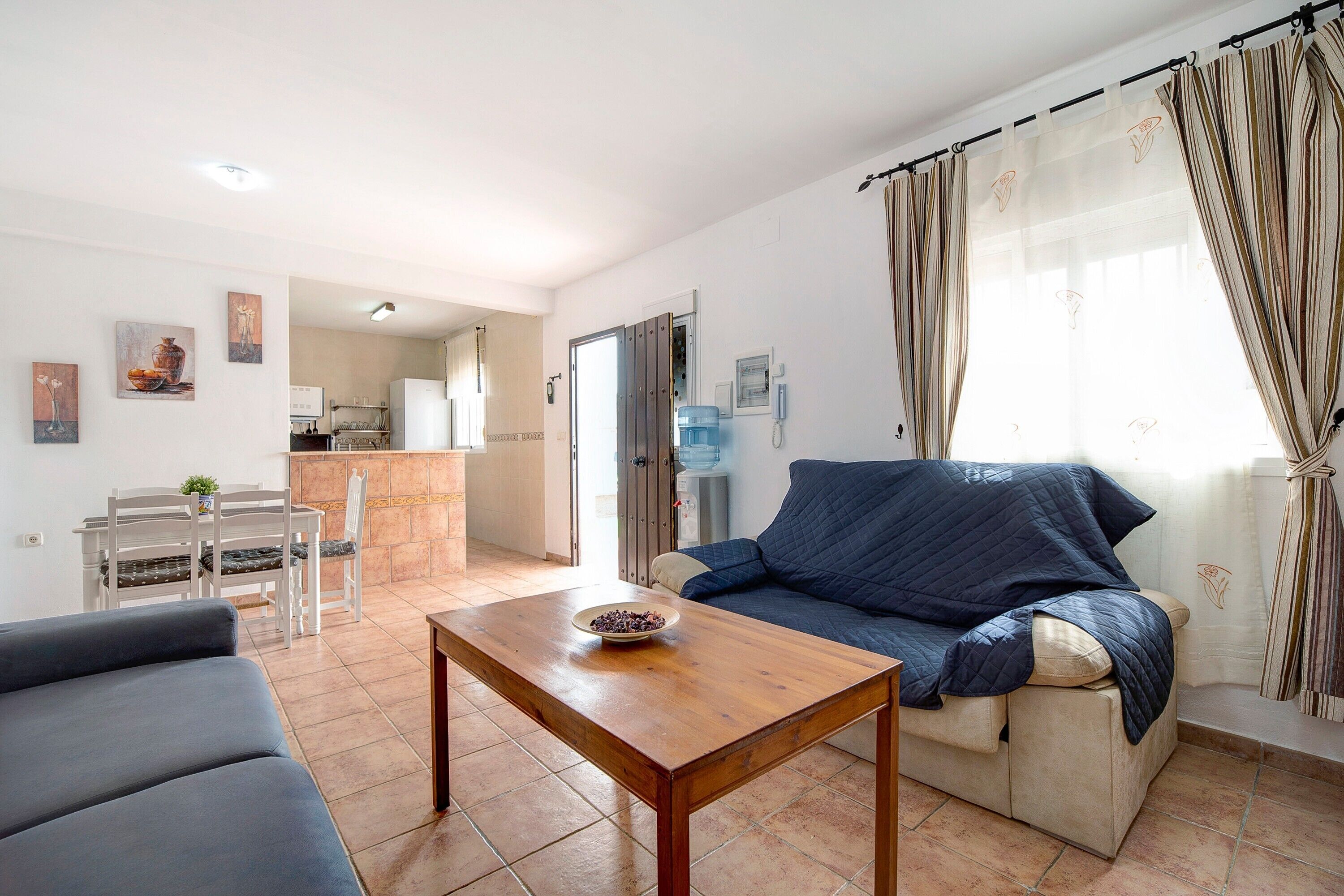 Una sala de estar con sofá, una mesa de centro y un comedor con sillas.