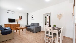 Ein Wohnzimmer mit einer Couch, einem Fernseher und einem Essbereich mit Stühlen und einem Tisch.