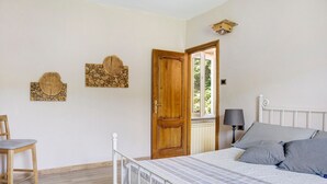 A bedroom with a bed, a chair, a wooden door, and two wall-mounted decorations. - Holiday Home 'La Rosa sul Lago' Pet-Friendly with Private Garden, Spa, and Wi-Fi (Osiglia)