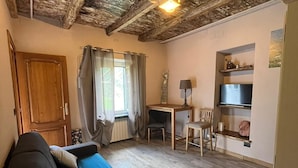 A cozy room with a wooden ceiling, a sofa, a table, and a TV. - Holiday Home 'La Rosa sul Lago' Pet-Friendly with Private Garden, Spa, and Wi-Fi (Osiglia)