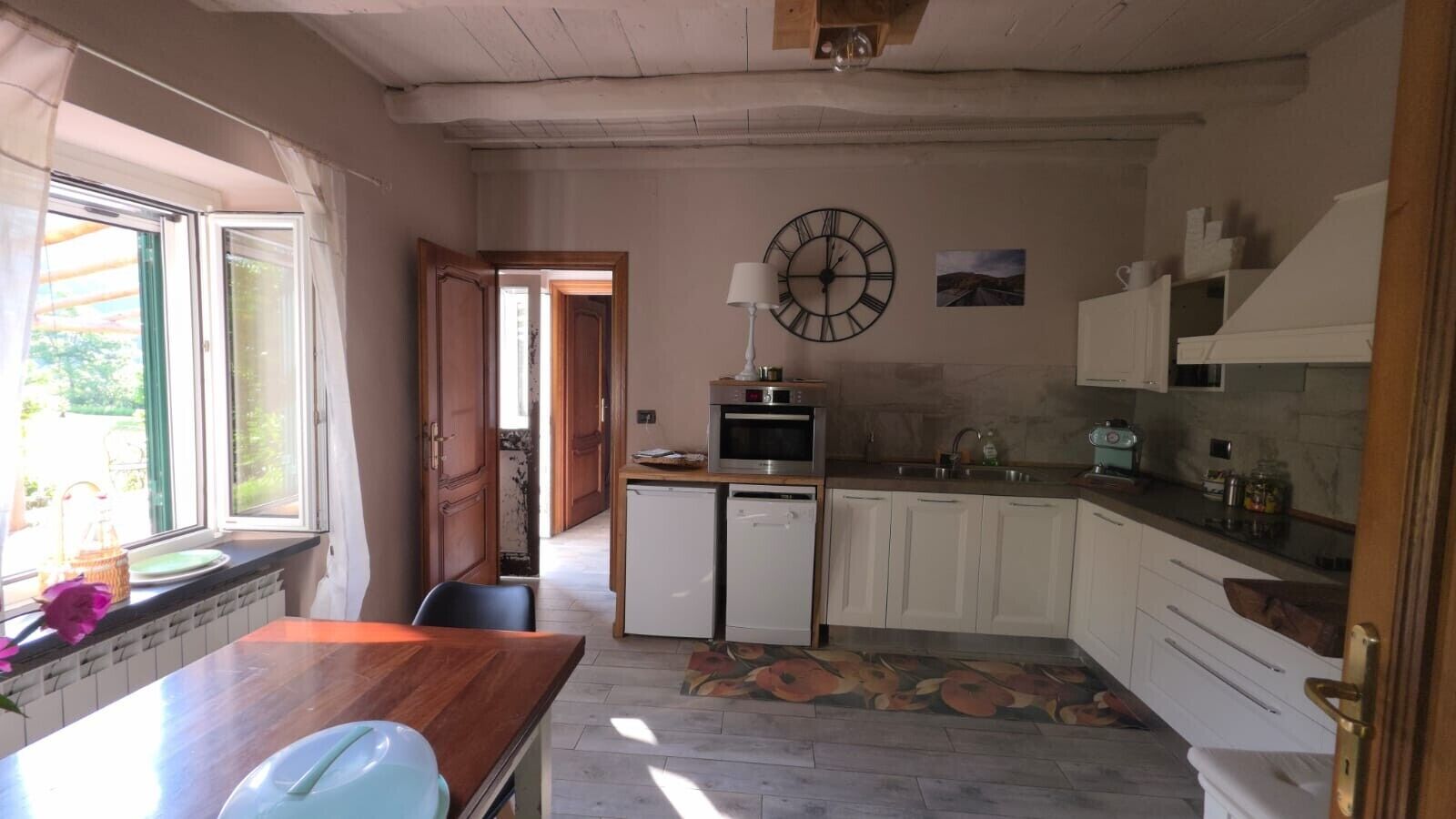 A kitchen with a wooden table, a microwave, and a sink.
