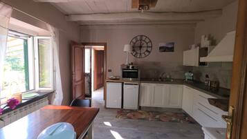 A kitchen with a wooden table, a microwave, and a sink.
