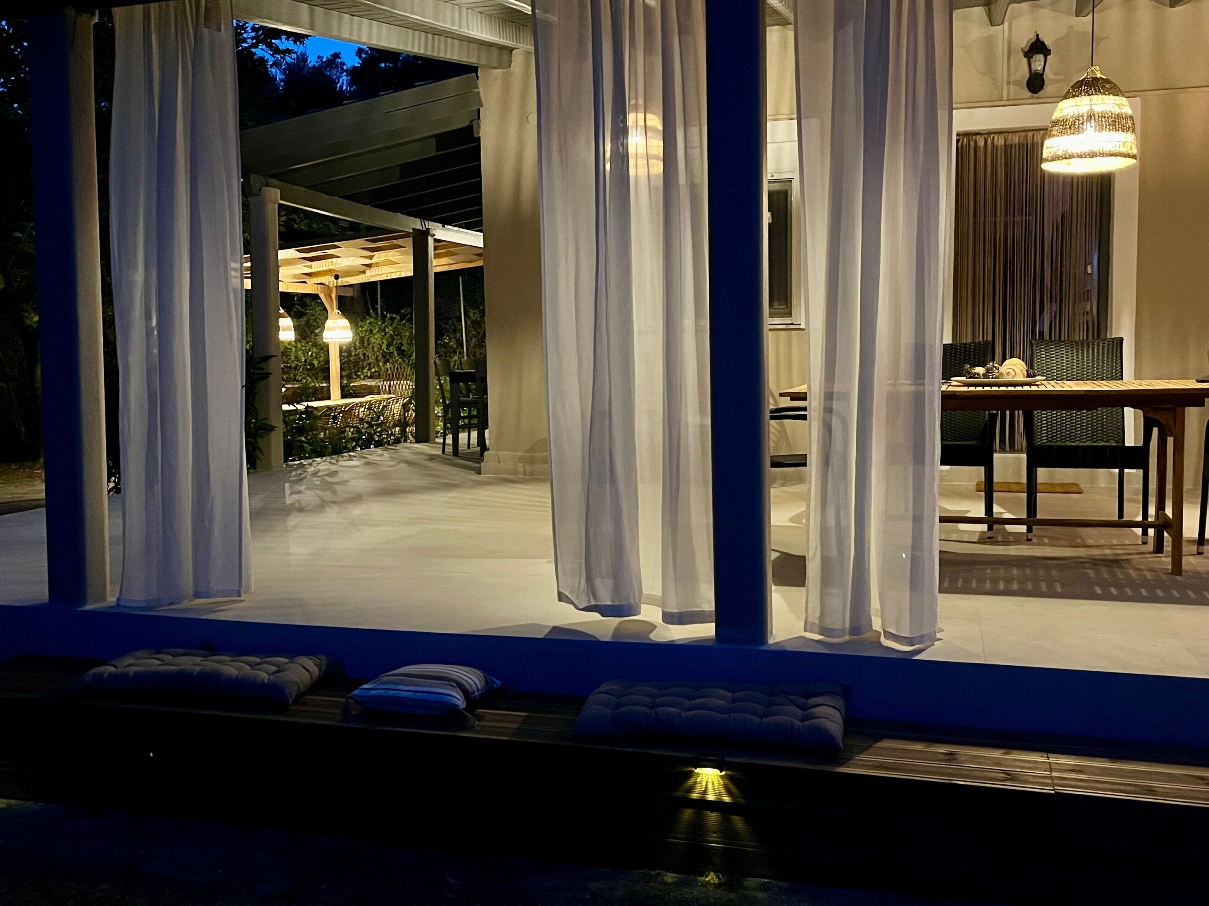 An outdoor seating area with a pool, curtains, and a table with chairs.