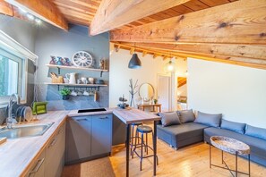 A modern kitchen with a built-in island, bar stools, and a seating area with a sofa and a small round table.
