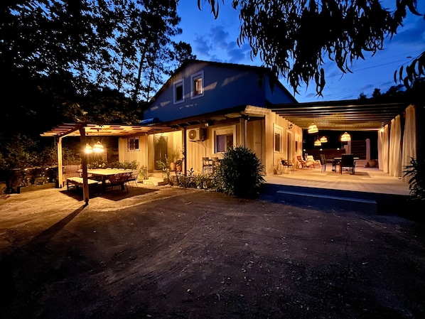A house with a covered patio, outdoor seating, and a pool area.