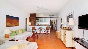 Habitación de hotel con zona de comedor, televisión y ventilador de techo.