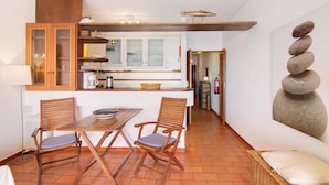 Una cocina compacta con armarios de madera, una mesa de comedor con sillas y una escultura de piedra en la pared.