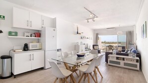 Una cocina moderna con armarios blancos, una mesa de comedor de cristal y vistas al exterior.