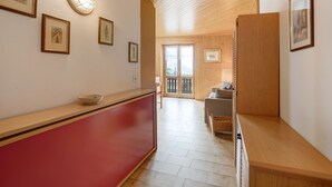 A hallway with a red counter, framed pictures on the wall, and a wooden ceiling. - Apartment 'Chalet Holly' with Mountain View, Shared Garden and Wi-Fi (Bormio)