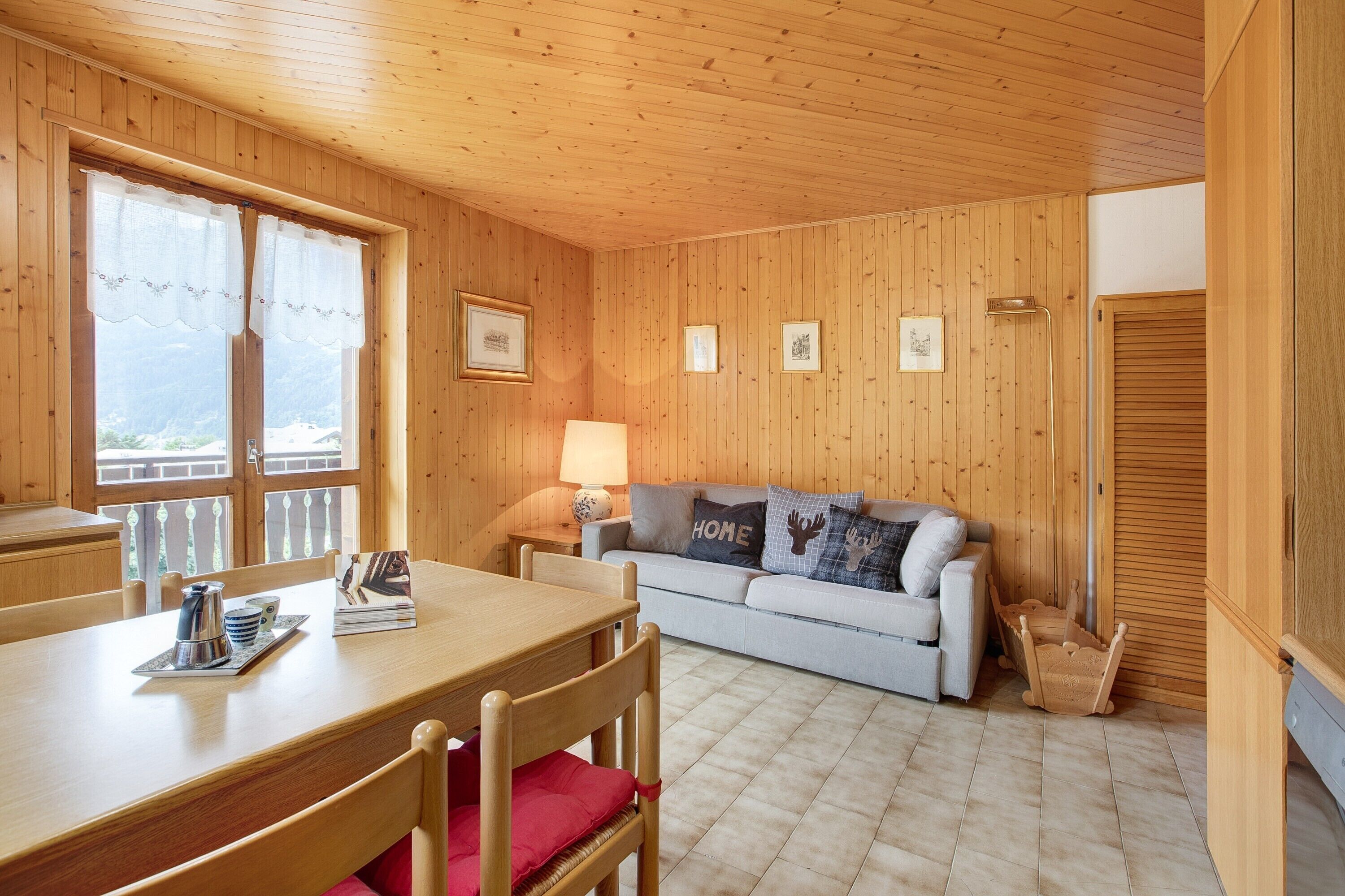 Una habitación con paneles de madera, una mesa de comedor, sillas, un sofá y una lámpara.
